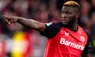 Victor Boniface con la maglia del Bayer Leverkusen indica una direzione ai compagni di squadra con il braccio
