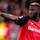Victor Boniface con la maglia del Bayer Leverkusen indica una direzione ai compagni di squadra con il braccio