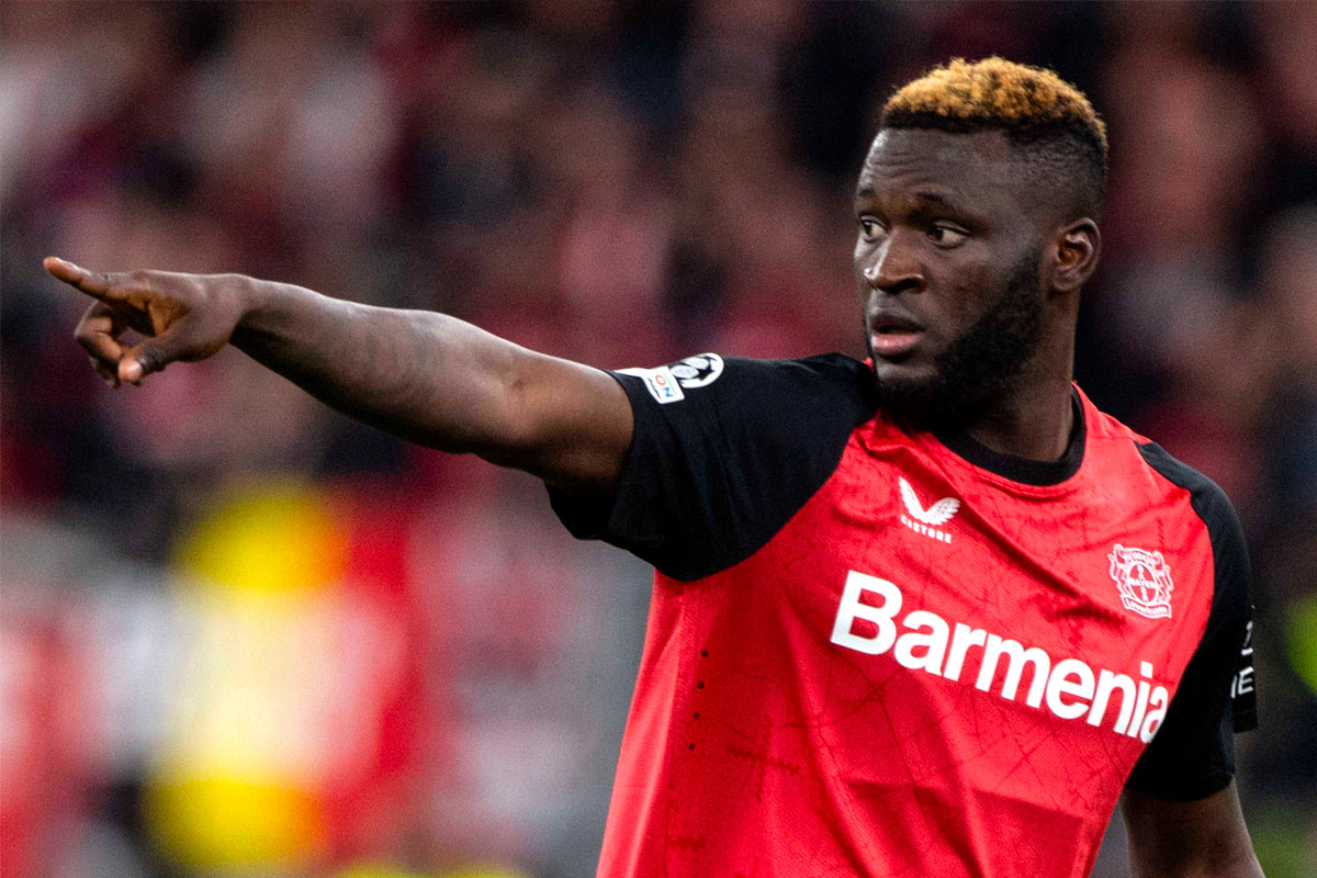 Victor Boniface con la maglia del Bayer Leverkusen indica una direzione ai compagni di squadra con il braccio